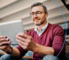 A man with a tablet in his hand looks at the onOffice Online Marketing Consulting website.