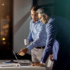Two men with a laptop in front of them: One man shows the other something on the screen in onOffice enterprise.