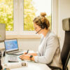 Frau die am Schreibtisch sitzt und arbeitet