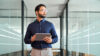 Mann mit Tablet in der Hand, der in die Ferne schaut