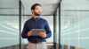 Mann mit Tablet in der Hand, der in die Ferne schaut