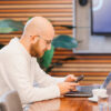 Alex Malievski bei der Arbeit vor Handy und Laptop