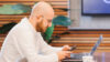 Alex Malievski bei der Arbeit vor Handy und Laptop
