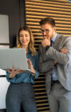 Eine Frau und ein Mann in einem modernen Büro schauen gemeinsam auf einen Laptop