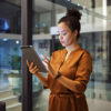 Frau mit Tablet vor Glasfront
