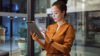 Frau mit Tablet vor Glasfront