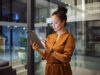 Frau mit Tablet vor Glasfront