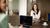 Zwei Frauen sitzen an einem Meetingtisch mit Laptop und Tablet