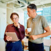 Mann mit Kaffee und Frau mit Laptop in der Hand
