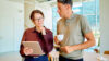 Mann mit Kaffee und Frau mit Laptop in der Hand